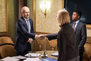 Attorney and client shaking hands over table with papers